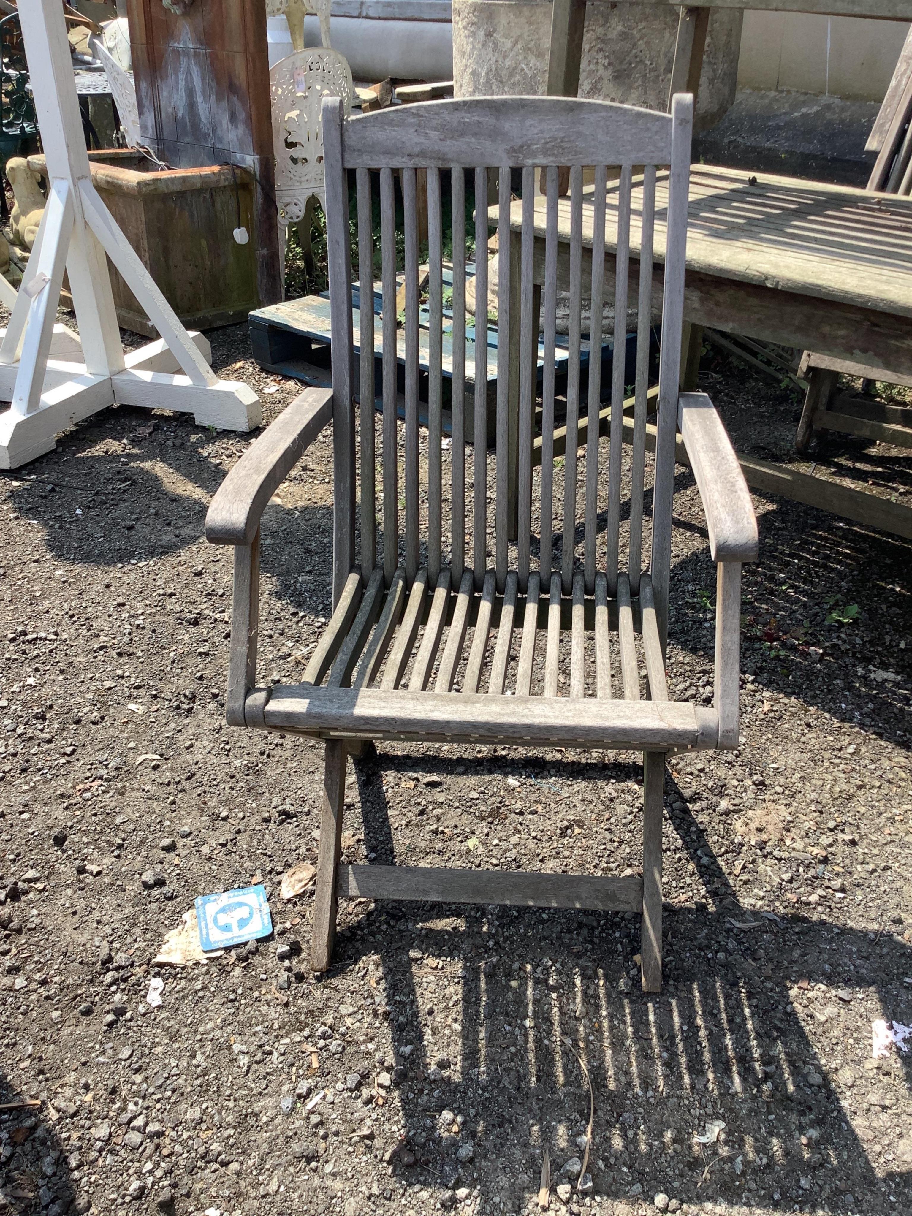A set of four weathered teak folding garden armchairs, width 52cm, height 98cm, together with a rectangular garden table and bench. Condition - poor to fair